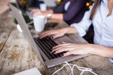 Young woman using laptop at home office. Modern office interior,