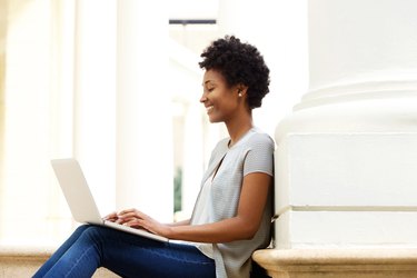 Young african woman sitting outside using laptop