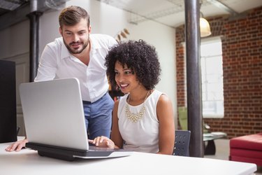 Casual business team looking at laptop together