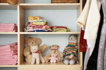 Stuffed animals, clothing and towels on shelves in closet