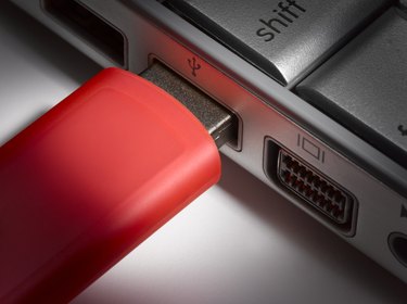 Red USB flash hard drive plugged into laptop, close-up