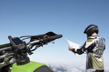 Biker reading map, focus on handlebar in foreground