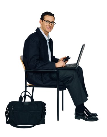 Businessman sitting on chair with laptop computer and cell phone