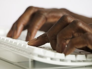 Close-up of a man's hands working on a computer keyboard