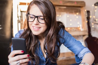 Young beautiful hipster woman using smart phone at office