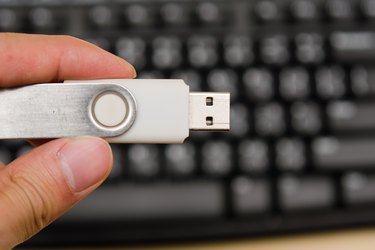 USB thumb drive with hand holding on keyboard background