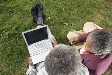 Senior African couple using laptop on grass outdoors