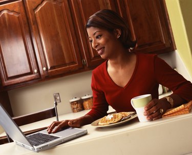 Woman using laptop and eating