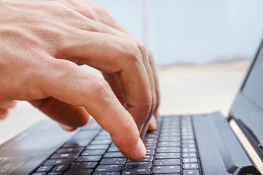 closeup hands on laptop keyboard typing