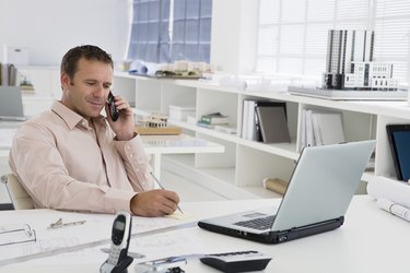 Businessman using laptop while on cell phone