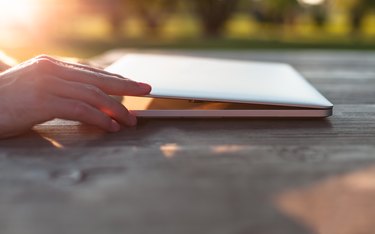 Man opening his laptop on a wooden table