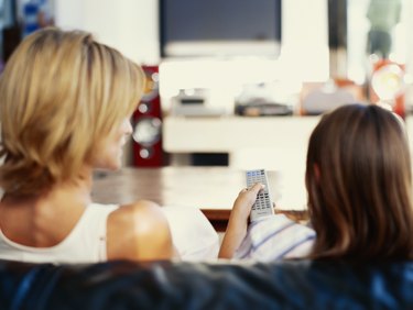 Mother watching television with her daughter (6-9)