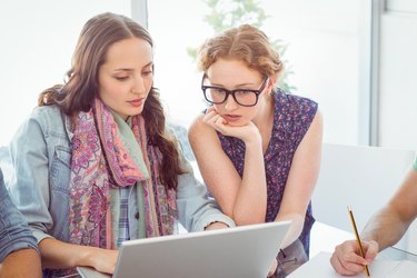 Two women well versed in fashion staring at laptop screen