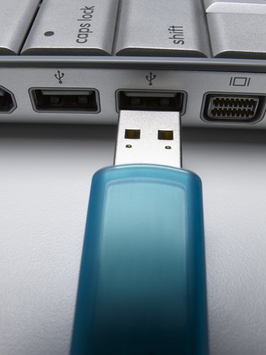 Turquoise USB flash drive about to connect to laptop, close-up