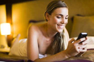 Woman text messaging on a mobile phone in a hotel room, Papeete, Tahiti, French Polynesia