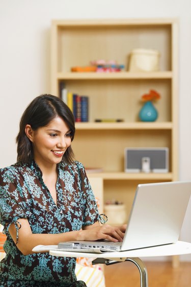 Mid adult woman using laptop, smiling