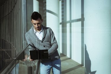 Handsome young man working at computer and listening to music