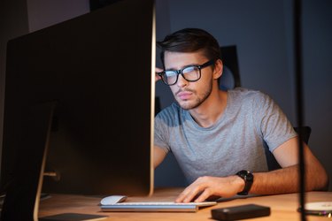 Thoughtful man thinking and working with computer in dark room