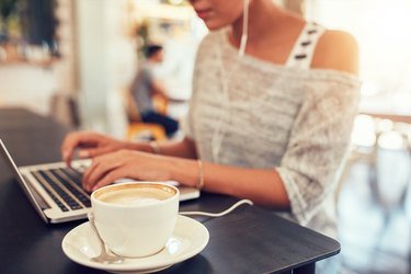 Cup of coffee on cafe table with a woman