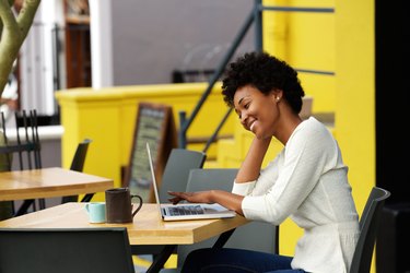 Happy woman using laptop at cafe