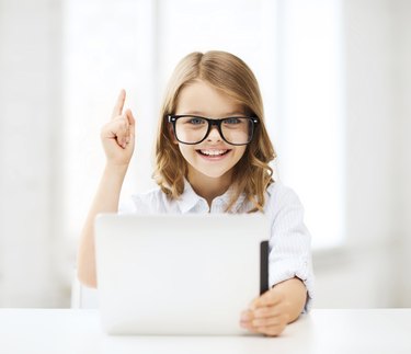 smiling girl in glasses with tablet pc at school