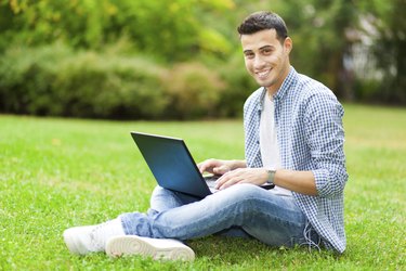 Student using laptop on the grass
