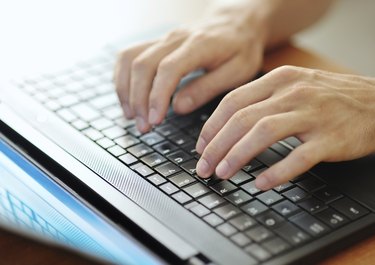 male hands typing on a laptop pc keyboard