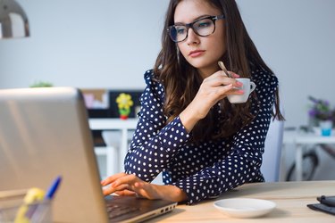 Beautiful young woman working with laptop in her office.