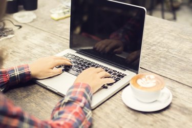 woman typing on a laptop with cup of coffee