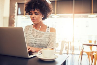 Beautiful young woman working on laptop at cafe