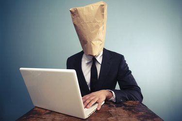 Businessman with bag over head working on computer