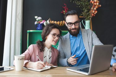 Modern team working in cafe with laptop, smartphone with coffee