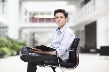 Teenage boy sitting in office chair, looking away