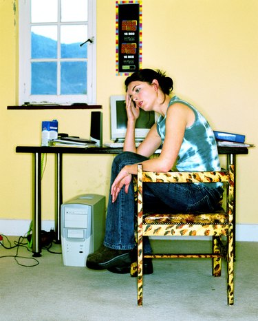 Young woman sitting next to a computer with a hand on her head