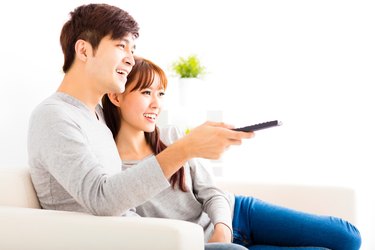 happy young couple watching tv in living room