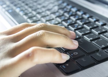 Hand typing on laptop keyboard.