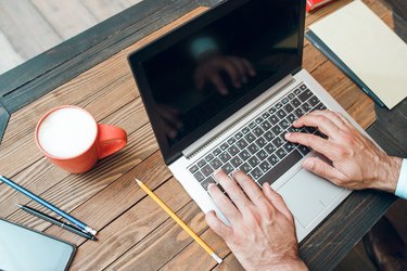 Male hands typing on laptop keyboard, mockup