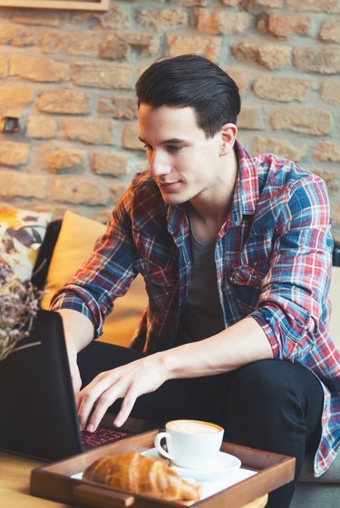 Young man sitting at a cafe, using a laptop