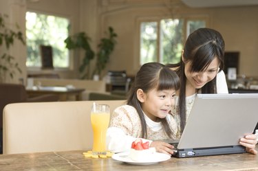 Mother and daughter using laptop at a cafe