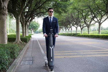 Man in suit ride electric scooter