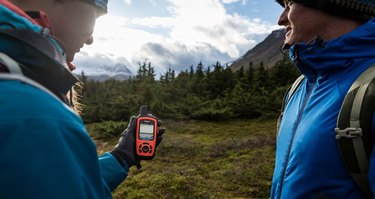 Photo of two outdoor adventurers looking at their Garmin inReach global satellite communications device.