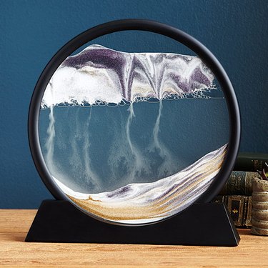 Photo of moving sand art in a black circular container.
