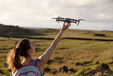 Photo of a girl in a large field launching DJI's Mavic Pro drone into the air.