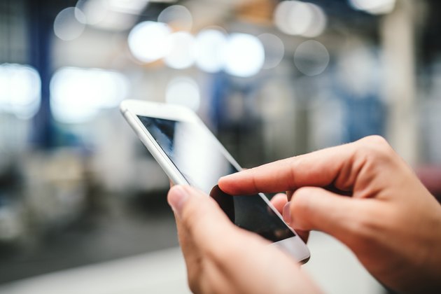 Close-up of female hands in factory using smartphone. Copy space.