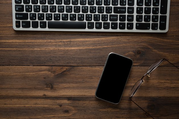 Directly Above Shot Of Keyboard And Mobile Phone With Eyeglasses On Table