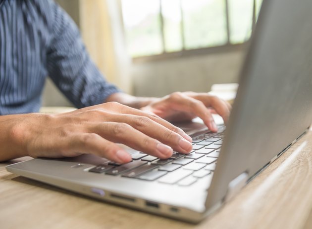 Businessman at a desk in an office typing on a laptop computer
