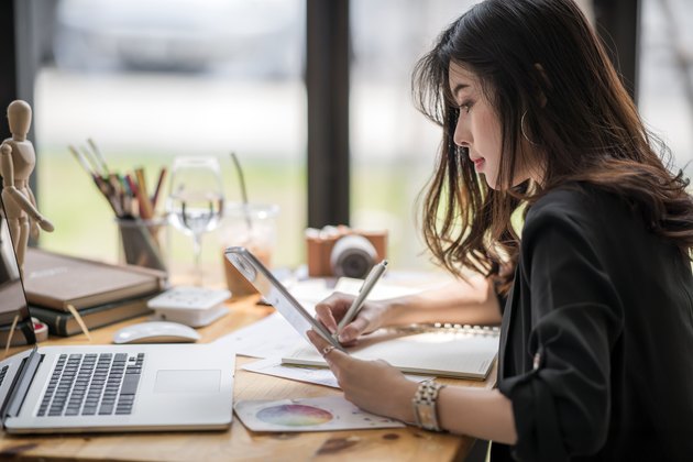 female designer working with paperwork and looking at tablet screen