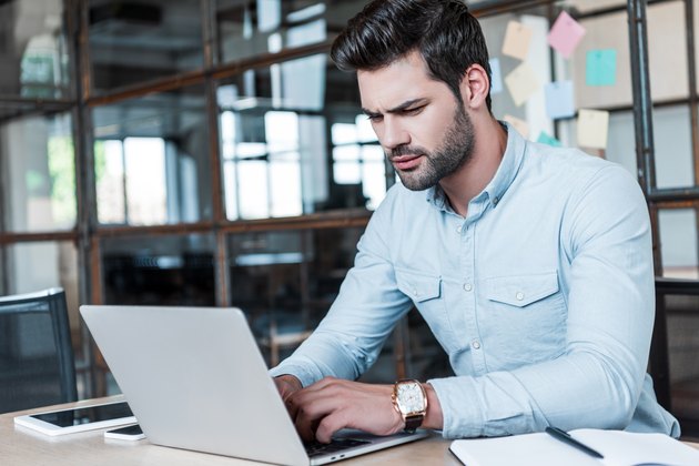 focused young businessman using laptop at workplace