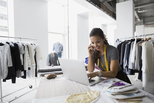 Fashion designer talking cell phone and using laptop