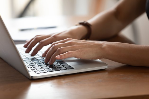 Close up female hands typing on keyboard, using laptop